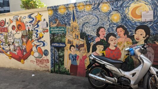 Illustration de street art représentant des femmes sur un scooter, peint sur un mur à Bangkok