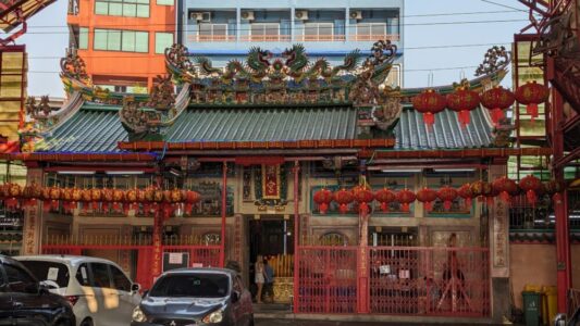 Illustration d'un temple à Chinatown, Bangkok, avec un dragon sculpté, des lanternes colorées et l'animation de la ville en arrière-plan