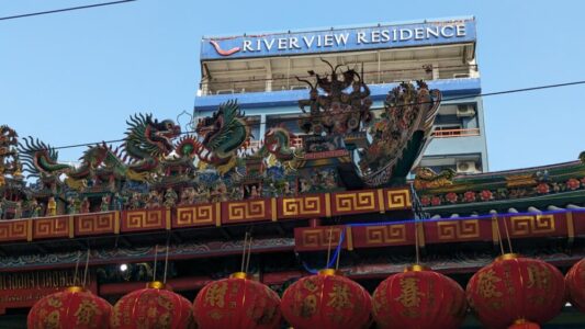 Illustration d'un temple à Bangkok avec un dragon sculpté, des lanternes colorées et un ciel bleu en arrière-plan