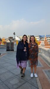 Illustration de deux amies souriantes devant un temple à Bangkok, partageant un moment joyeux