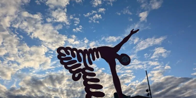 Un street art vibrant représentant un homme dansant entouré d'une forme en ressort, avec un ciel bleu éclatant en arrière-plan. L'œuvre capture le mouvement et l'énergie créative