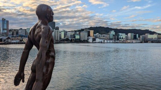 Sculpture d'un homme en plein art, statue face au port de Wellington, avec des mains tendues vers l'avant