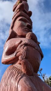 Sculpture maorie en bois rouge sur Mont Victoria à Wellington, avec un ciel bleu nuageux en arrière-plan