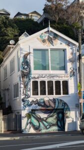 Street art à Wellington : un tūī éclatant sur la façade d'une maison, entre nature et architecture