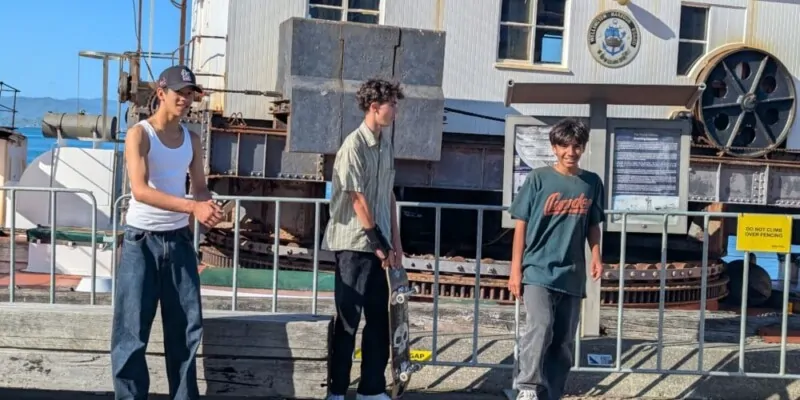 Trois jeunes hommes pratiquent du skateboard dans une rue animée de Wellington