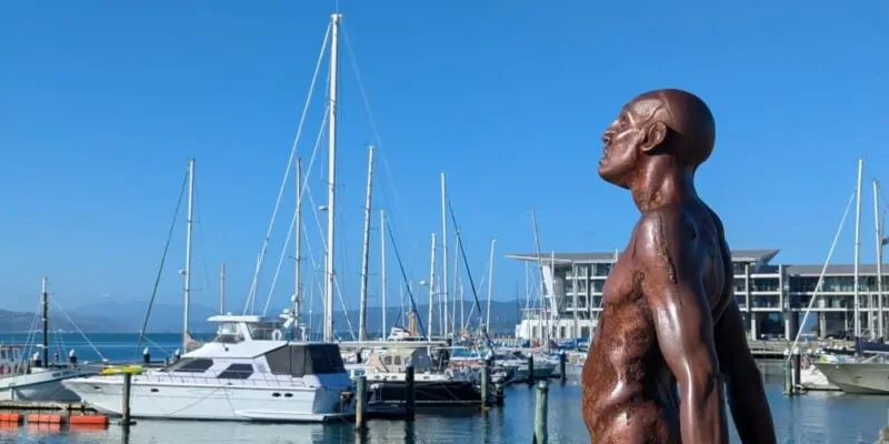 Statuette en bronze au port de Wellington sous un ciel bleu. Bateaux amarrés en arrière-plan