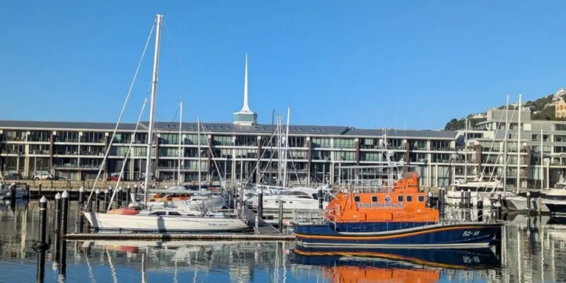 Bateaux orange et blancs amarrés au port de Wellington, reflets calmes sur l’eau Scène portuaire paisible aux couleurs éclatantes, typique du bord de mer néo-zélandais